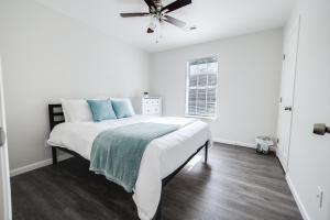 een witte slaapkamer met een bed en een plafondventilator bij Trailside Townhouse - Close to Downtown & Bike Trails in Bentonville