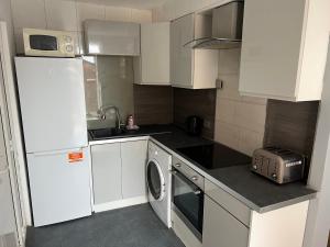 a small kitchen with white cabinets and a washer at Modern Studio Apartment Manchester with Pool Table and Private Driveway in Denton