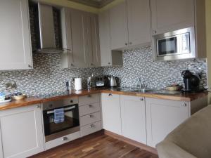 a kitchen with white cabinets and a microwave at Hewlett Apartments in Cheltenham