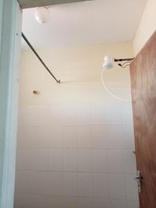 łazienka z prysznicem wyłożona białymi kafelkami. w obiekcie Georgia Furnished Apartments w mieście Machakos