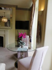 a dining room with a glass table with flowers on it at Hewlett Apartments in Cheltenham
