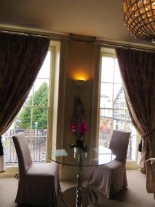 a dining room with a table and chairs and windows at Hewlett Apartments in Cheltenham