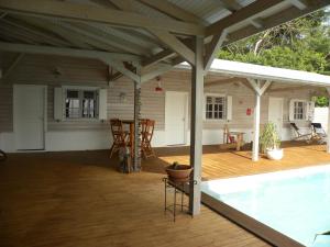a screened in porch with a swimming pool and a house at VILLA DIAMANTILLES - MAISON D'HOTES in Le Diamant