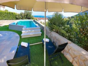 uma piscina com um guarda-sol e duas cadeiras e uma mesa com um guarda-sol em Villa Vita,free wifi,nearby sea em Opatija