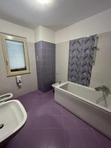Łazienka z fioletowymi kafelkami, wanną i umywalką w obiekcie Casa dello Yoga w mieście Colonnella