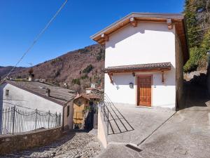 a white building with a wooden door and a fence at Holiday Home Casa del Sole by Interhome in Casasco Intelvi