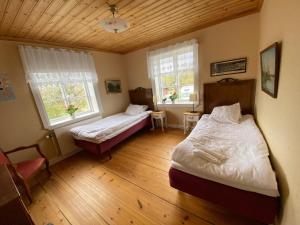 a bedroom with two beds and two windows at Spjutsbygds Gårds Bed and Breakfast in Rödeby