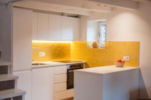 a kitchen with white cabinets and a yellow tile wall at CASA TON, junto a Baqueira y Aigüestortes in Sorpe