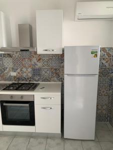 una cucina bianca con piano cottura e frigorifero di Residence R&B Tyrrhenum a Monte di Procida