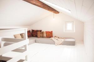 a white attic bedroom with a bed and a ladder at CASA TON, junto a Baqueira y Aigüestortes in Sorpe