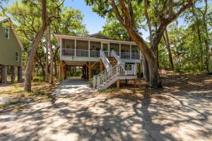 a large house with a wrap around porch with trees at Geechee Girl in Edisto Beach