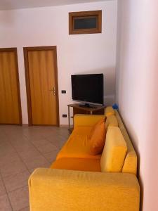 un divano giallo in soggiorno con TV di Holiday mode EVA a Partinico