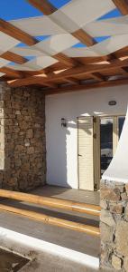 a porch with a wooden ceiling and a stone wall at Airport Studios in Aggelika