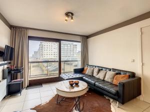 een woonkamer met een zwarte leren bank en een tafel bij Appartement 'Plaza' te Oostduinkerke - Bad in Oostduinkerke-Bad