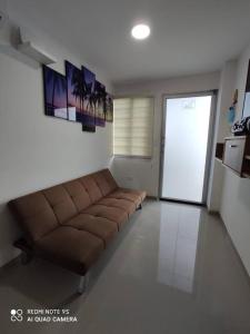 sala de estar con sofá marrón frente a una puerta en Departamento amoblado en Tonsupa, en Tonsupa