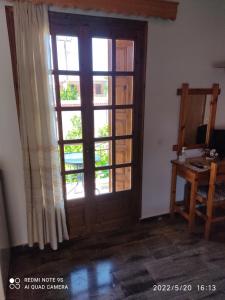 Una puerta en una habitación con una ventana y una mesa en Studios Maro en Skala Kallonis