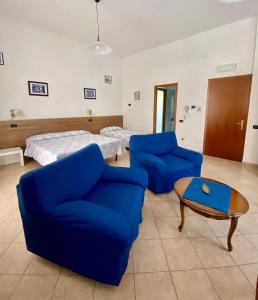 ピニョーネにあるLocanda Da Marcoの青い椅子2脚とベッド1台が備わる客室です。