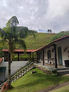 una casa con una palmera delante de ella en Pousada Cachoeira, en Serra Negra