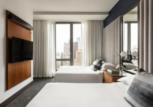ニューヨークにあるキンプトン ホテル エヴェンティのベッド2台とテレビが備わるホテルルームです。