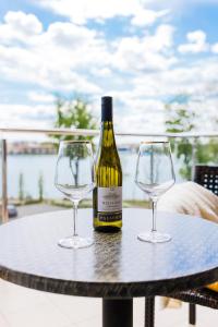 a bottle of wine and two wine glasses on a table at Willa Port Apartament Premium z widokiem na jezioro in Ostróda