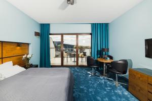 um quarto de hotel com uma cama, uma mesa e cadeiras em Willa Port Apartament Premium z widokiem na jezioro em Ostróda