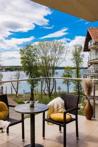 a patio with a table and chairs and a view of the water at Willa Port Apartament Premium z widokiem na jezioro in Ostróda
