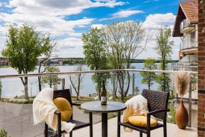 uma varanda com mesa e cadeiras e vista para a água em Willa Port Apartament Premium z widokiem na jezioro em Ostróda
