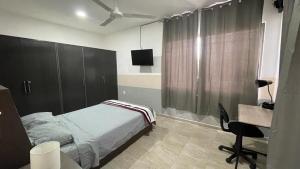 Schlafzimmer mit einem Bett, einem Schreibtisch und einem TV in der Unterkunft Departamento Orellana 11 in Chetumal