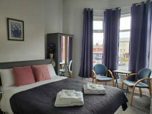 a bedroom with a bed and chairs and a window at Brooklyn Hotel in Blackpool