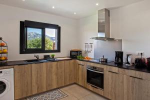 una cocina con armarios de madera y una ventana en apart Levante shared swimming pool bbq, en Calenzana