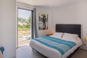 een slaapkamer met een bed en een glazen schuifdeur bij apart Levante shared swimming pool bbq in Calenzana