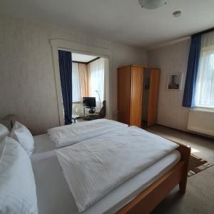 a bedroom with a large white bed and a desk at Haus Daheim in Braunlage