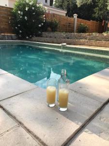 two glasses of orange juice sitting next to a swimming pool at Gîtes en B&B Le Clos de la Cerise in Châteauneuf-du-Pape