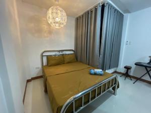 a small bedroom with a bed and a chandelier at Sto. Niño Residences Standard Room in Lucena