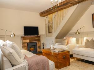 a living room with white furniture and a fireplace at Oma's Cottage in Moreton in Marsh