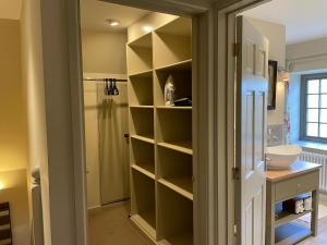 a bathroom with a closet with shelves and a sink at Oma's Cottage in Moreton in Marsh +23 photos