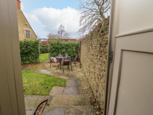 a door leading into a yard with a stone wall at Oma's Cottage in Moreton in Marsh