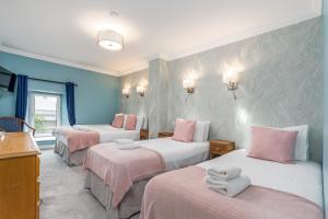 Zimmer mit 3 Betten mit rosa und weißer Bettwäsche in der Unterkunft Troysgate House in Kilkenny