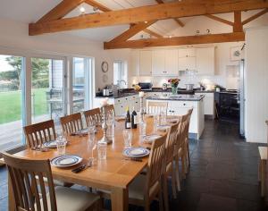 a large wooden table with chairs and a kitchen at Ossco in Polzeath +17 photos