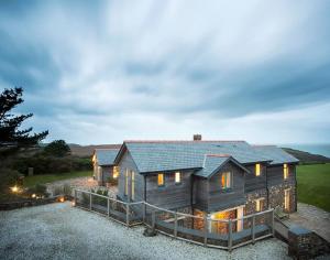 a large wooden house sitting on top of a field at Ossco in Polzeath
