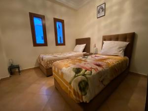 a bedroom with two beds and a table and two windows at Lilac's Garden Cabo Negro in Cabo Negro