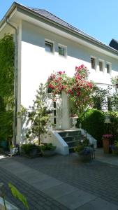 ein weißes Gebäude mit rosa Blumen davor in der Unterkunft Stadtvilla-Apartment mit Parkblick und bester Verkehrsanbindung in Bremerhaven