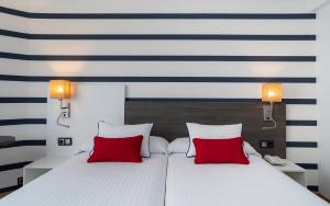 a bedroom with a bed with two red pillows at Medplaya Hotel Riudor - Adults Recommended in Benidorm