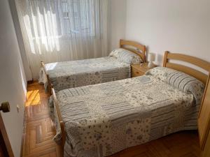 dwa łóżka w pokoju z oknem w obiekcie MAR DE BAIONA w mieście Baiona