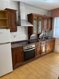 kuchnia z drewnianymi szafkami i białą lodówką w obiekcie MAR DE BAIONA w mieście Baiona