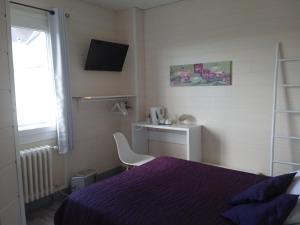 um quarto com uma cama roxa e uma cadeira em Hotel de la Gare em Noyers-sur-Cher