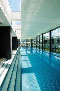 a large swimming pool in a building with glass windows at Crown Promenade Melbourne in Melbourne