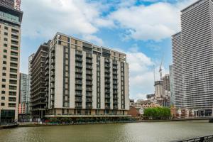 a tall building next to a river with buildings at South Quay Apartments Canary Wharf in London