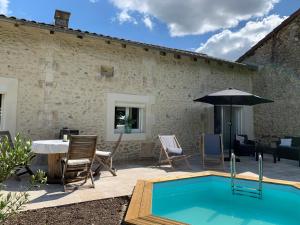um pátio com uma piscina, uma mesa e um guarda-sol em Maison de famille 24 em Trélissac