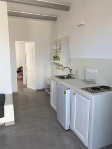 a white kitchen with a sink and a stove at Maganiotis Rooms in Kimolos